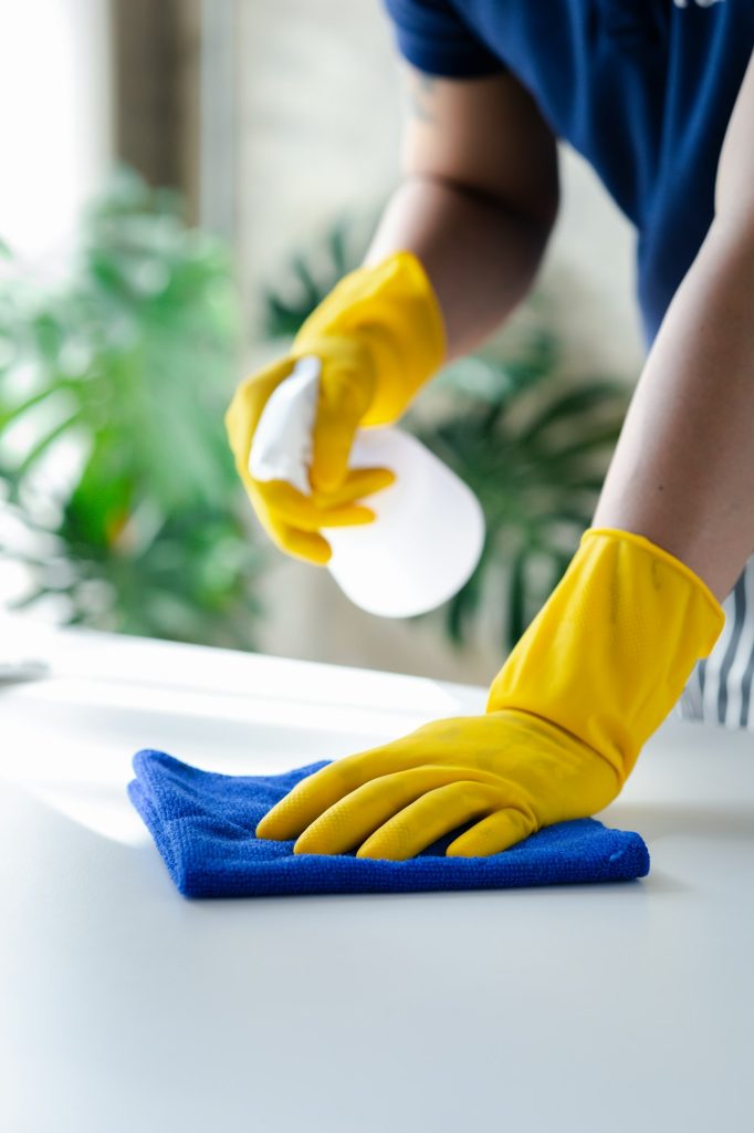 Person cleaning the room, cleaning staff is using cloth and spraying disinfectant.